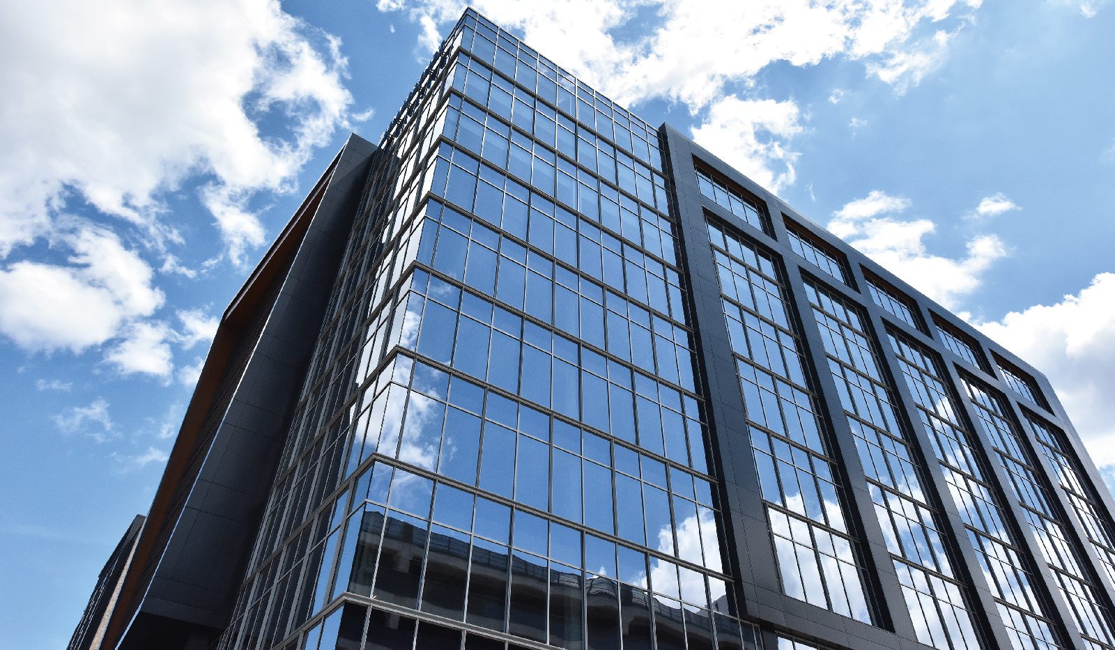 Bloc 83, Raleigh: a dark-framed glass office tower seen from below against clouds