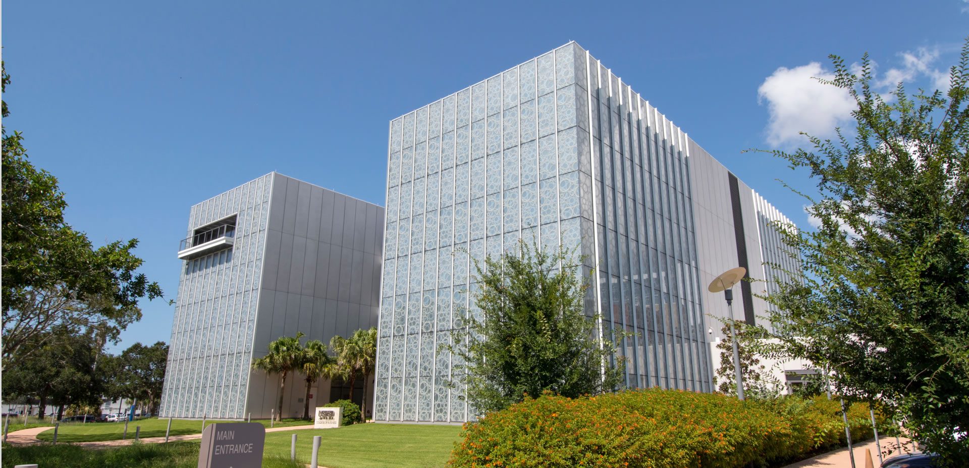 USFSP Kate Tiedemann College of Business, St. Petersburg: a glass building behind landscaping